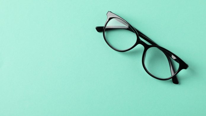 Glasses on mint background, space for text